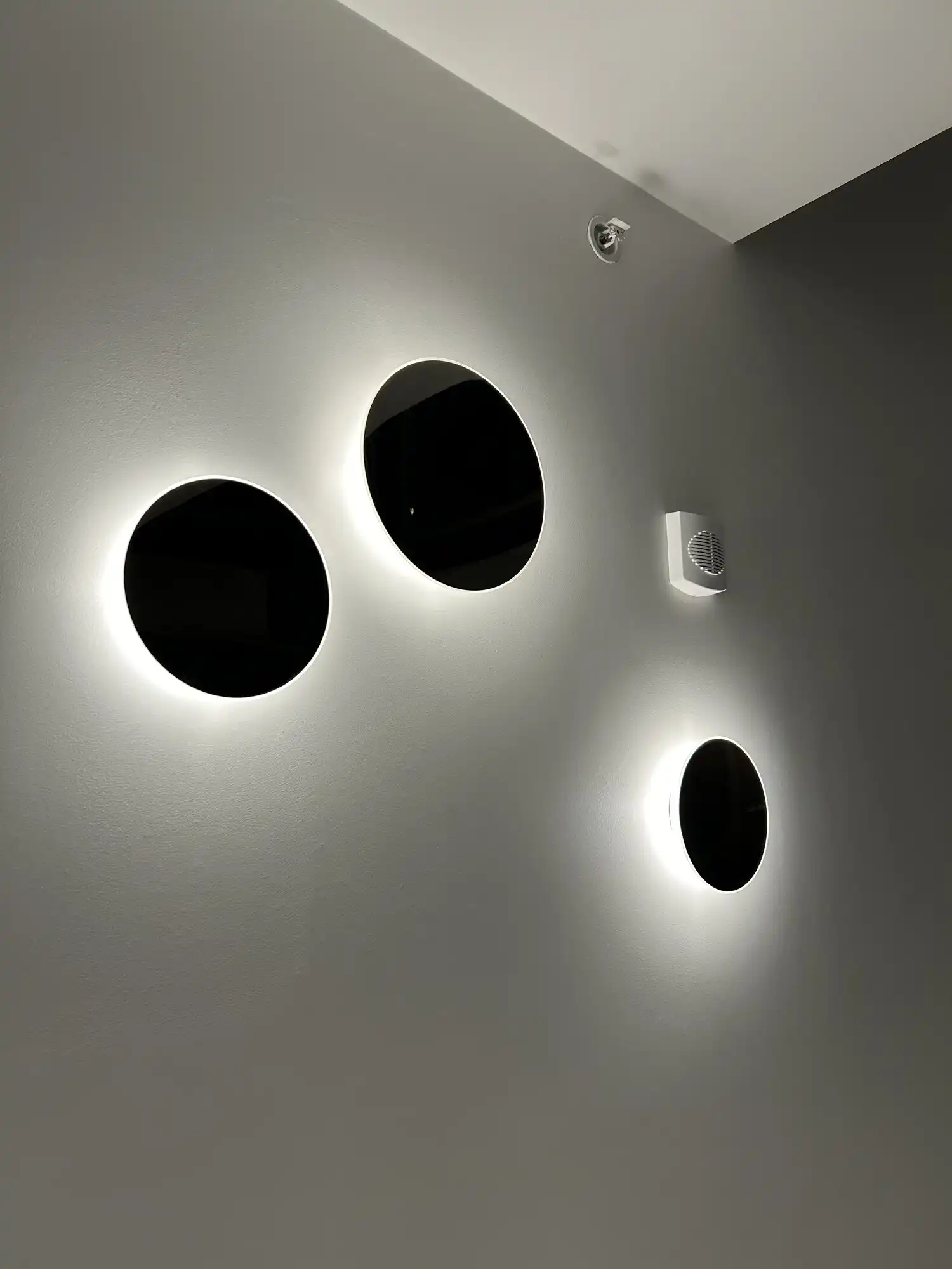 Backlit round LED wall sconces glowing on a bedroom wall, Bellevue condo lighting installation