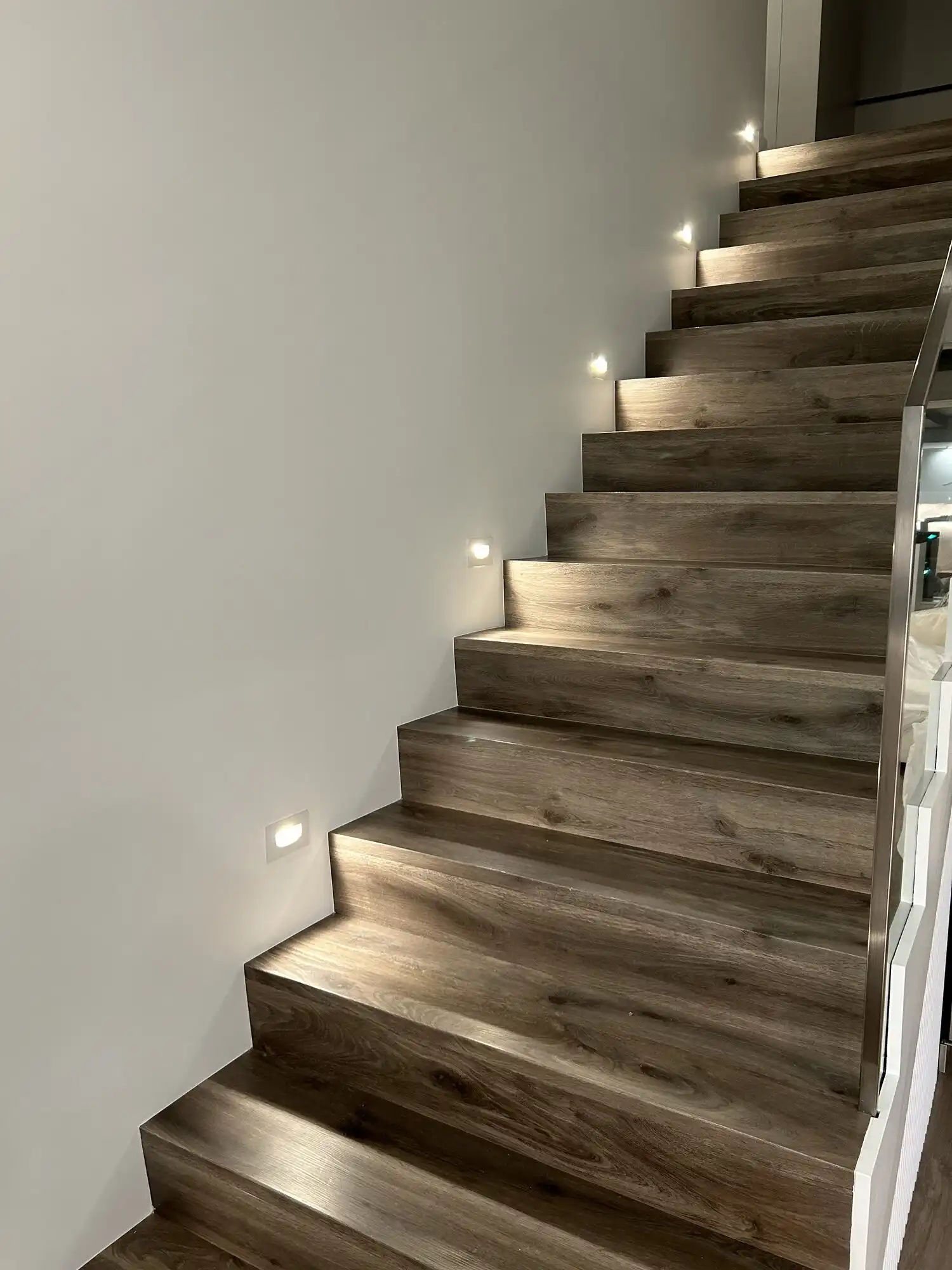 LED step lights lighting a wood staircase in a Bellevue luxury condo, installed by HB Power Electric