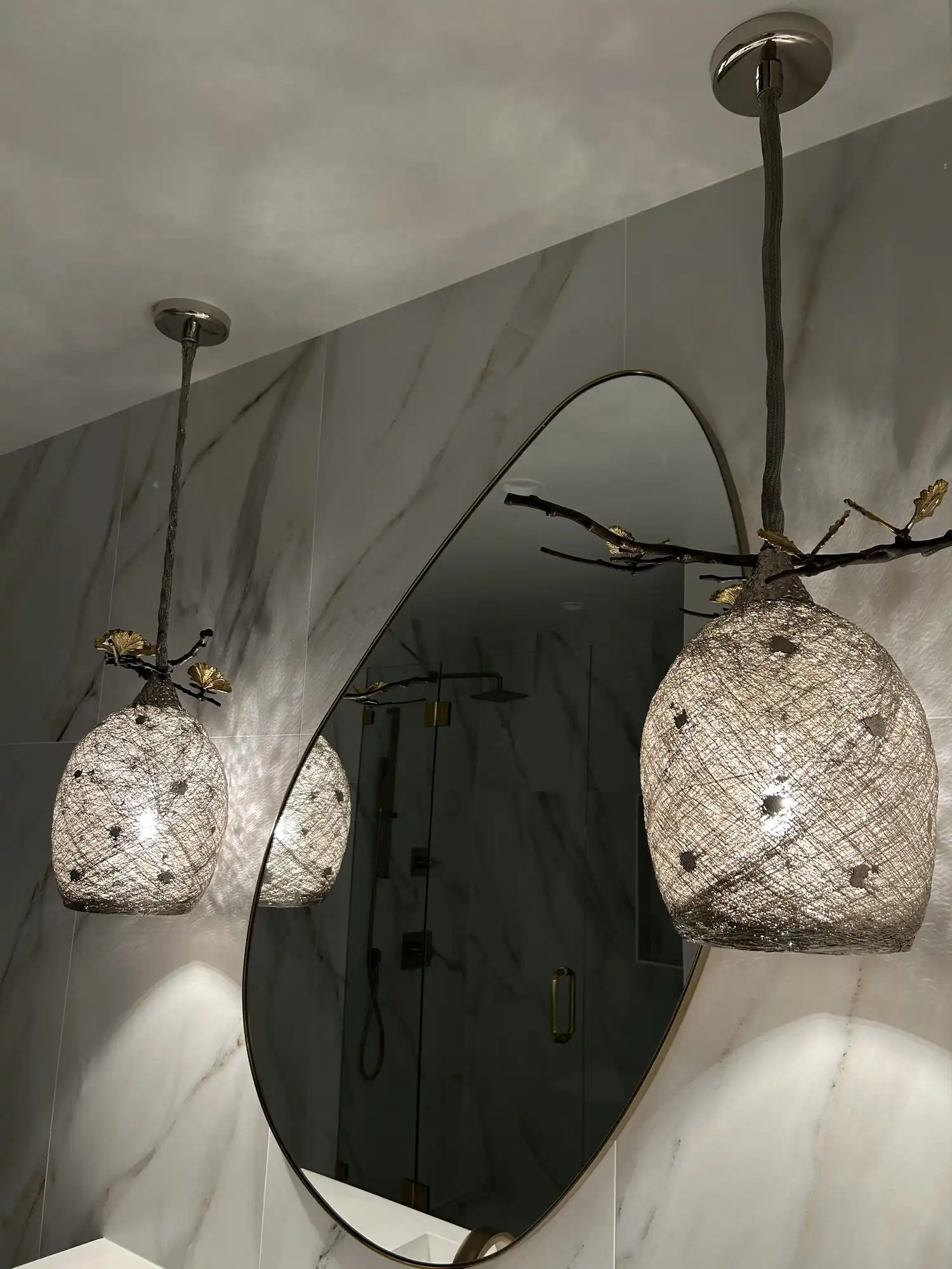 Designer branch-and-mesh pendant lights installed over a marble bathroom vanity in a Bellevue high-rise condo