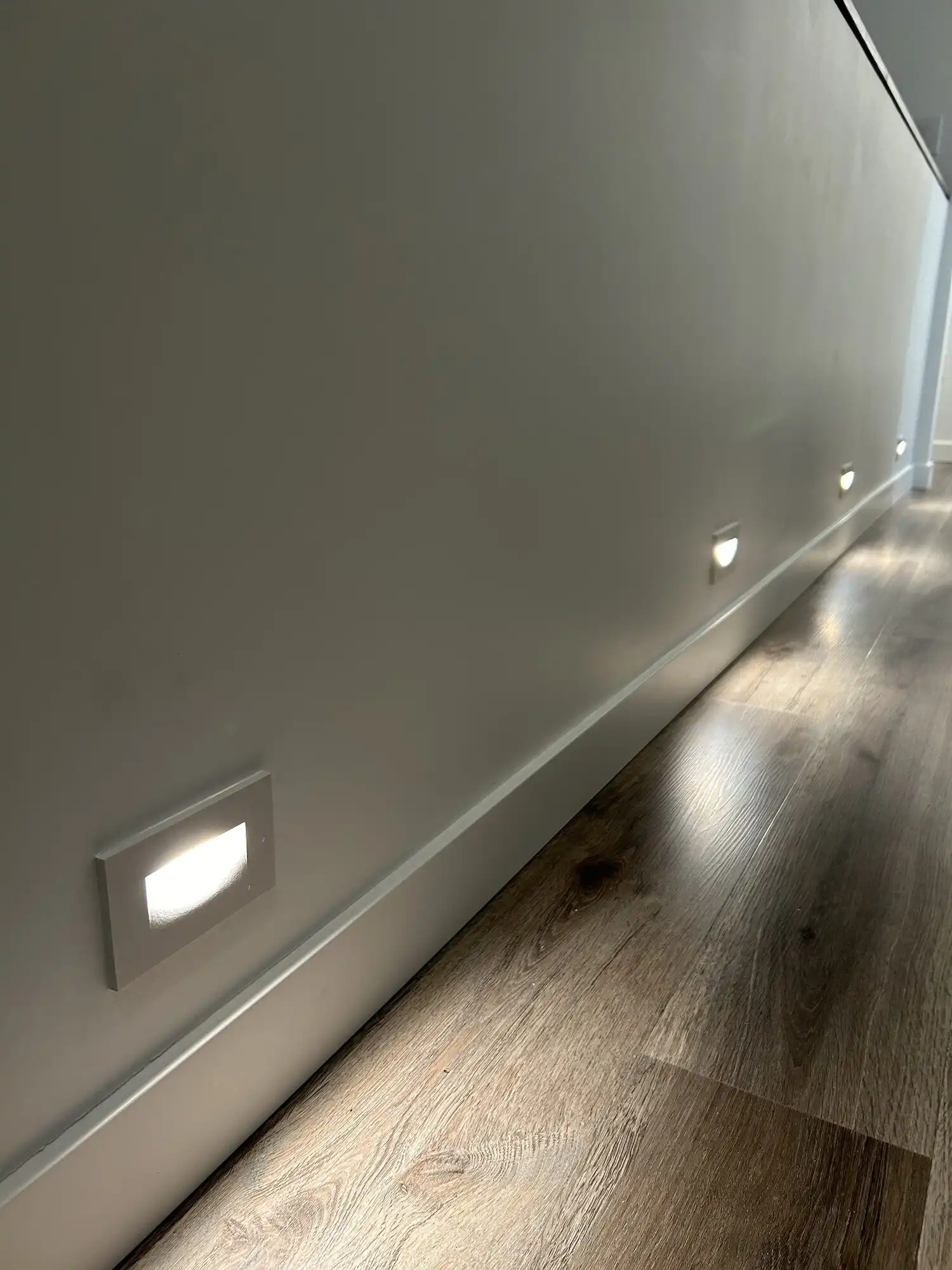Close-up of a recessed LED step light above the baseboard in a Bellevue luxury condo hallway