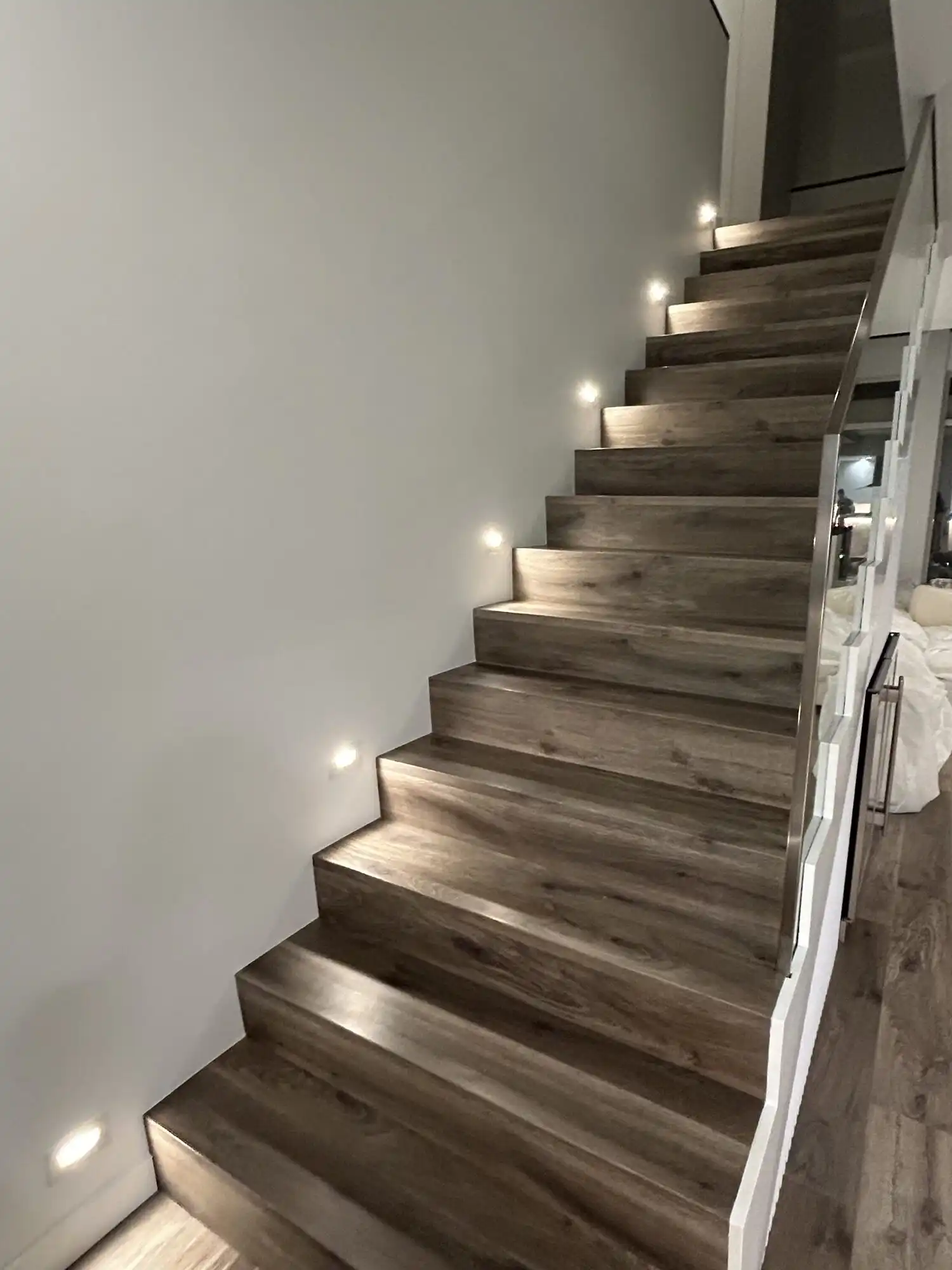 Recessed LED stair step lights installed along a wood staircase in a Bellevue high-rise condo by HB Power Electric