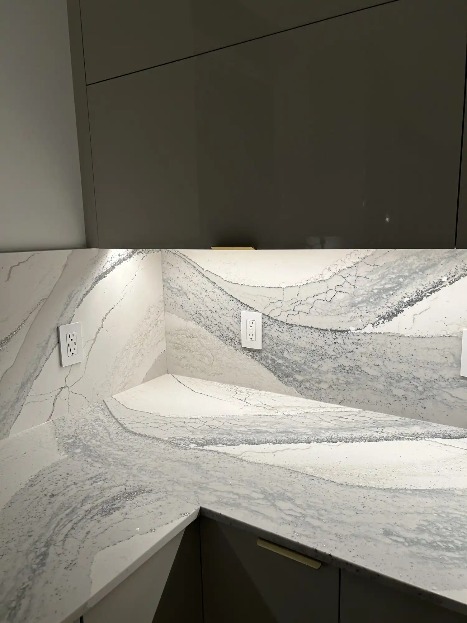 Under-cabinet LED lighting and new outlets on a quartz backsplash in a Bellevue high-rise condo