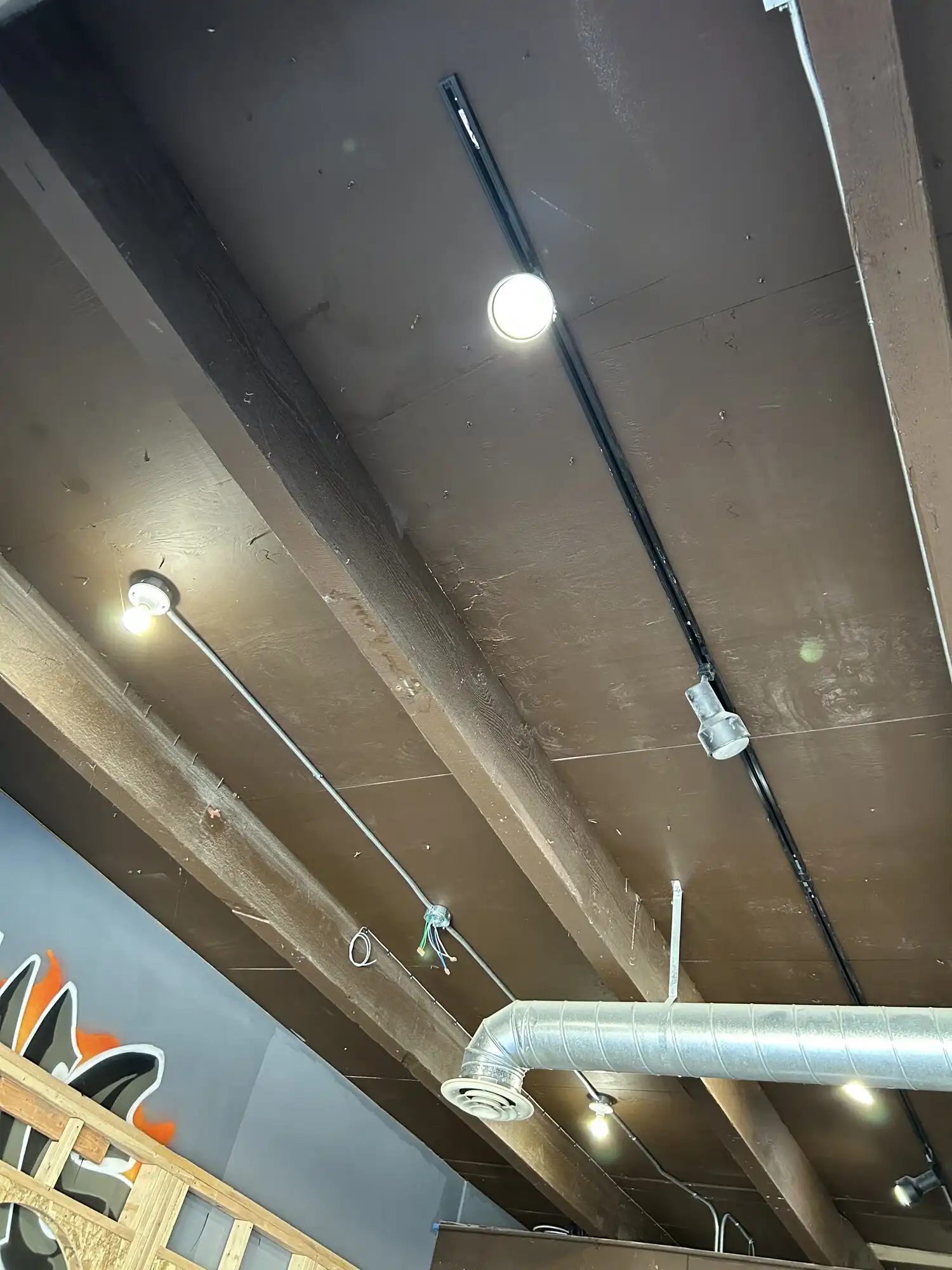 Surface conduit and track lighting installed on an exposed beam ceiling during a Federal Way restaurant tenant improvement